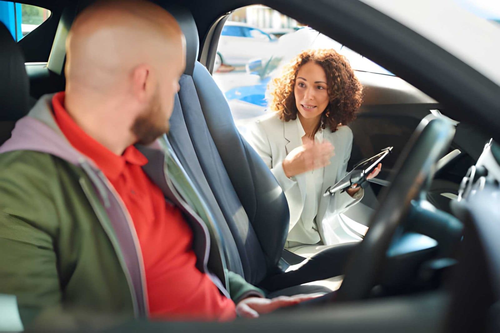 Used car dealers Bradenton professional showing details on tablet to customer seated in car