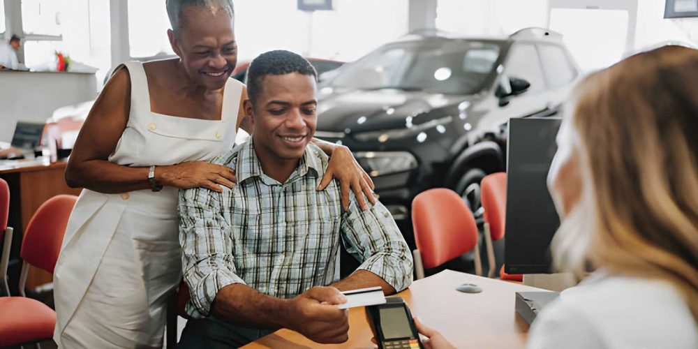 Buy here pay here Sarasota—customer making vehicle purchase payment with credit card at dealership desk.