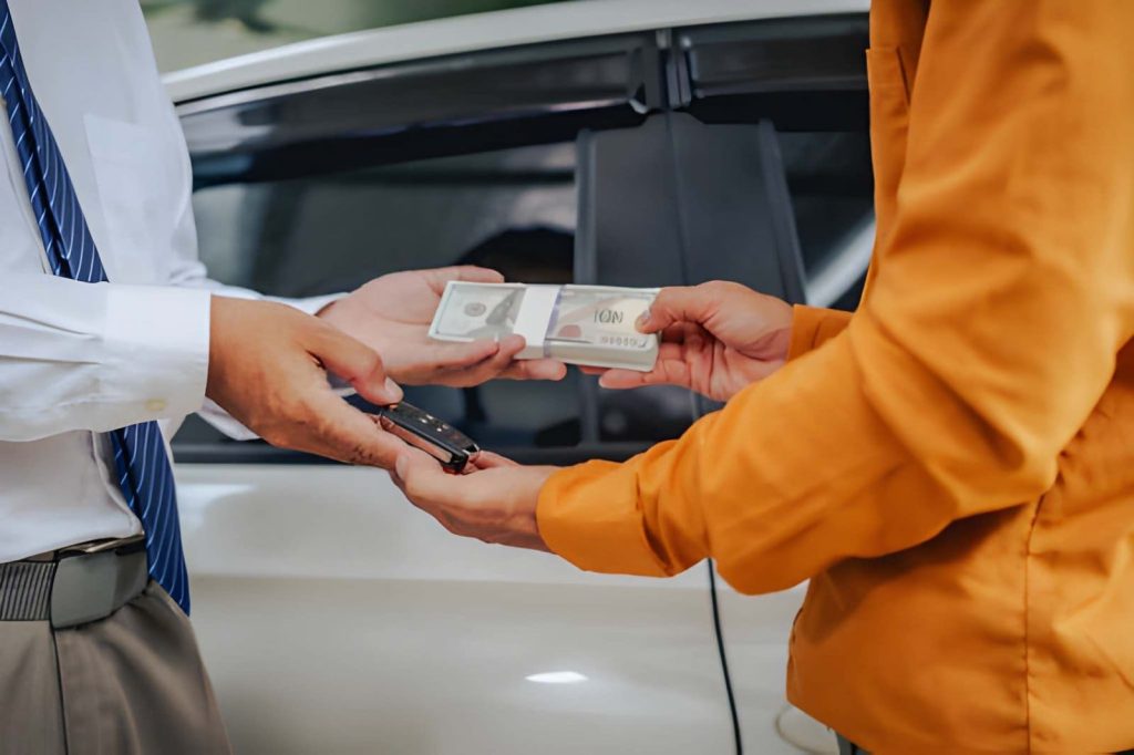 Buy here pay here Sarasota FL—customer exchanging cash for car keys in front of vehicle.