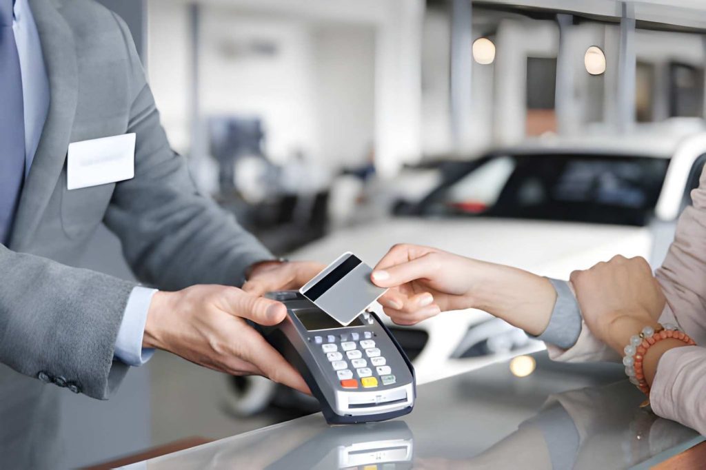 Buy here pay here Sarasota—customer making contactless car purchase payment with credit card at dealership.