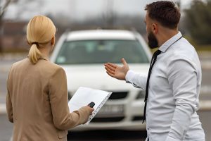 Used car dealers Bradenton—professionals inspecting white car and reviewing documents during evaluation.