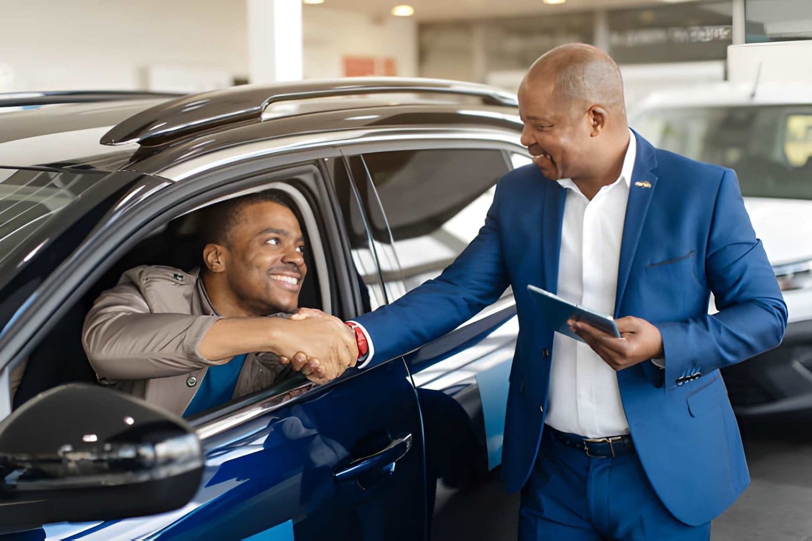 Auto sales in Sarasota FL customer shaking hands with dealer during car purchase agreement inside showroom.