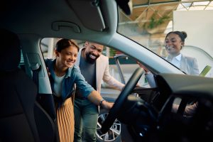 Buy here pay here auto loans Sarasota customers and dealer reviewing car interior with clipboard in showroom