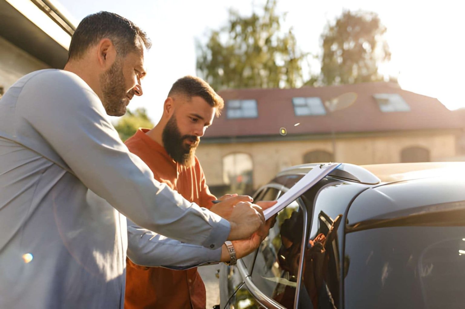 Bargain used cars Bradenton customers reviewing paperwork beside vehicle during outdoor dealership transaction.