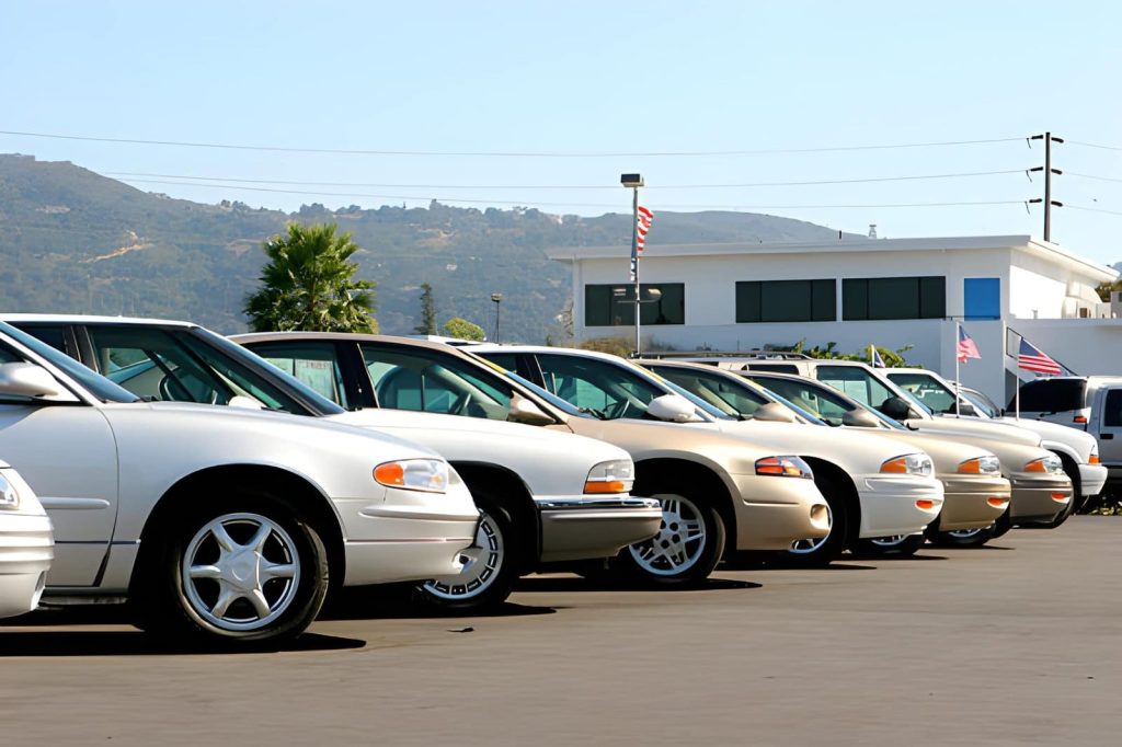 Bargain used cars Bradenton dealership lot with multiple sedans parked in rows under clear blue sky.