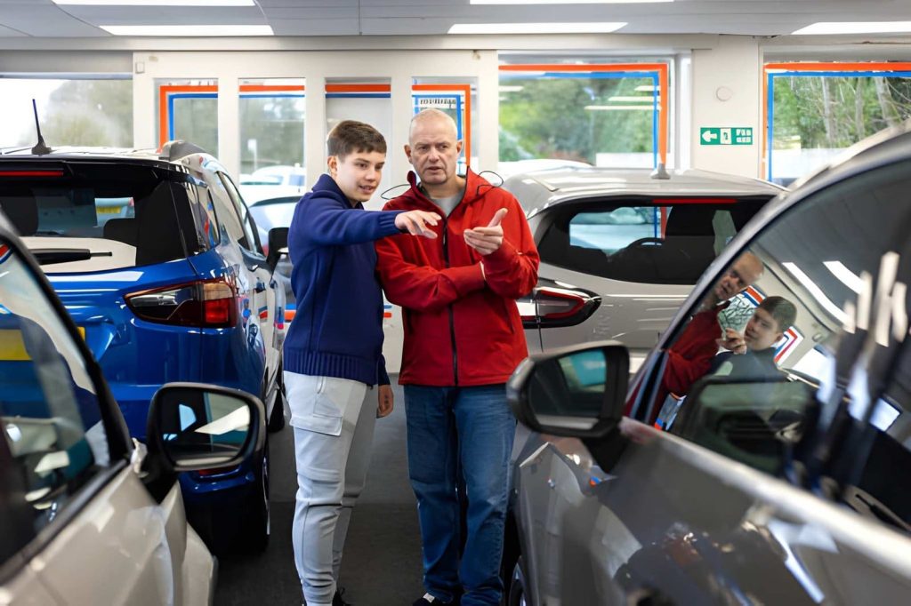 Used car dealers in Venice Florida customers discussing vehicle options inside bright showroom with multiple cars.