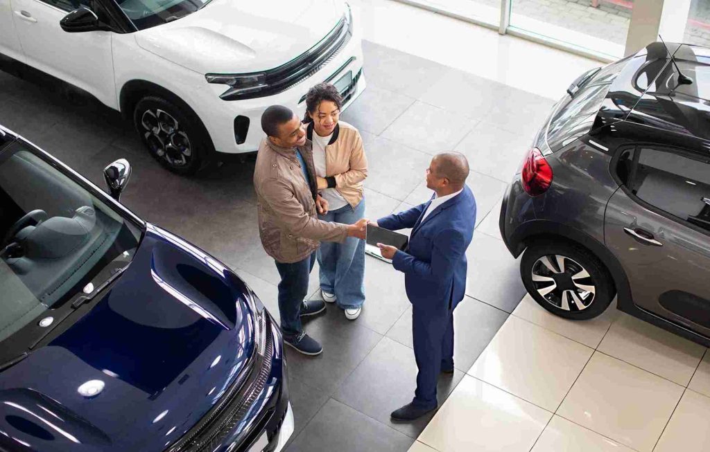 Car sales Sarasota FL dealership salesperson shaking hands with customers in showroom.