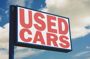 Used car dealers Venice Florida sign displaying "USED CARS" against a blue sky with light clouds.